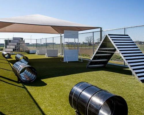 Fenced K-9 training yard with obstacle course and shade canopy