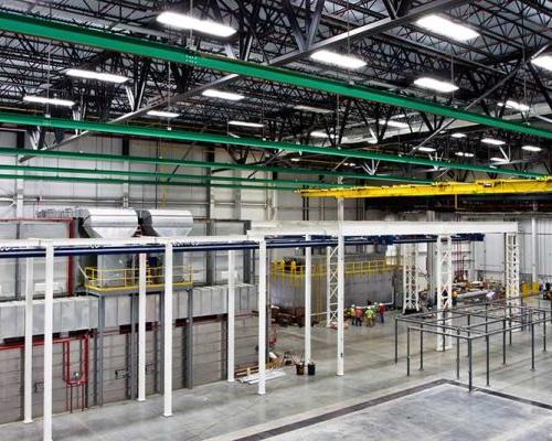 Interior of Spirit AeroSystems Composite Center. Large industrial room with green, yellow and white rafters.