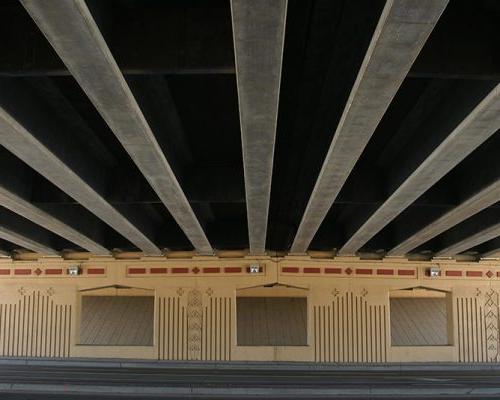 View of bridge piers and decking from beneath highway overpass